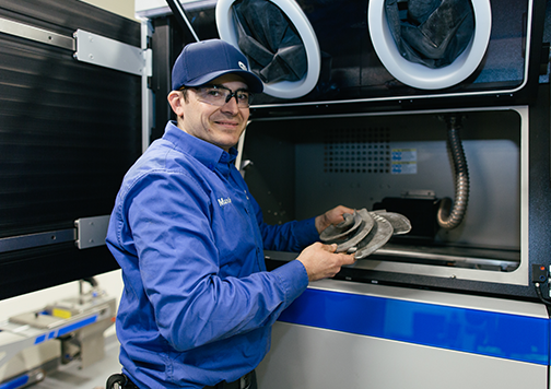 Man retrieving printed components from an industrial 3D printer